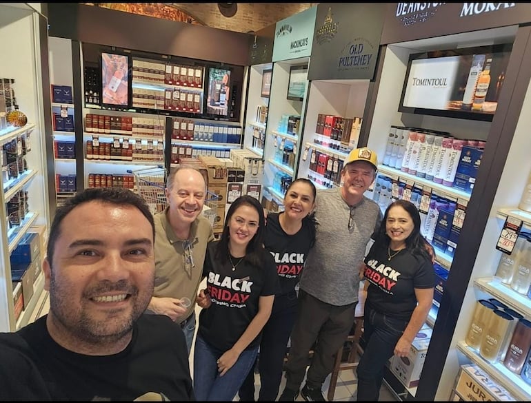 Vendedores posando con algunos clientes en una tienda de bebidas.