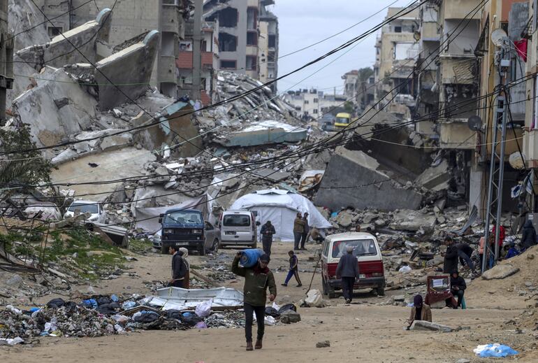 Palestinos caminan entre casas destruidas en el campamento de refugiados de Al Shatea en medio de un alto el fuego entre Israel y Hamás, en la ciudad de Gaza.