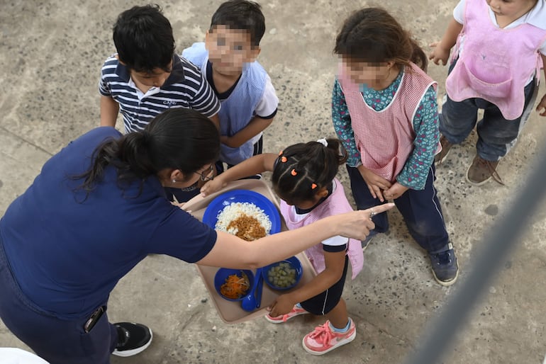 Niños reciben el almuerzo en el patio de una escuela, en Asunción.