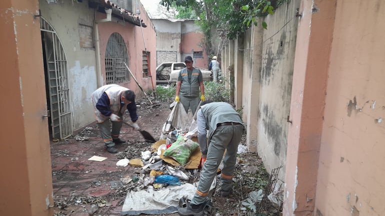 Funcionarios municipales limpian una casa abandonada de Asunción. 