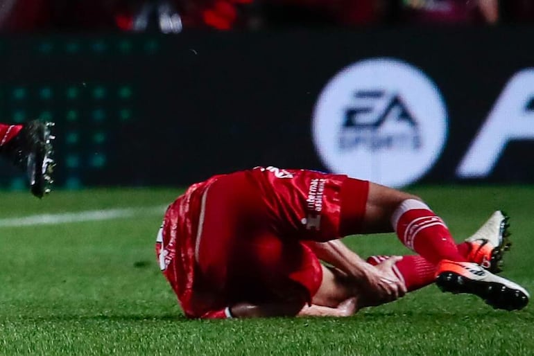 El argentino Luciano Sánchez, jugador de Argentinos Juniors, se toma de la rodilla después de una falta de Marcelo, futbolista de Fluminense en el partido de los octavos de final de la Copa Libertadores en el estadio Diego Armando Maradona, en Buenos Aires.