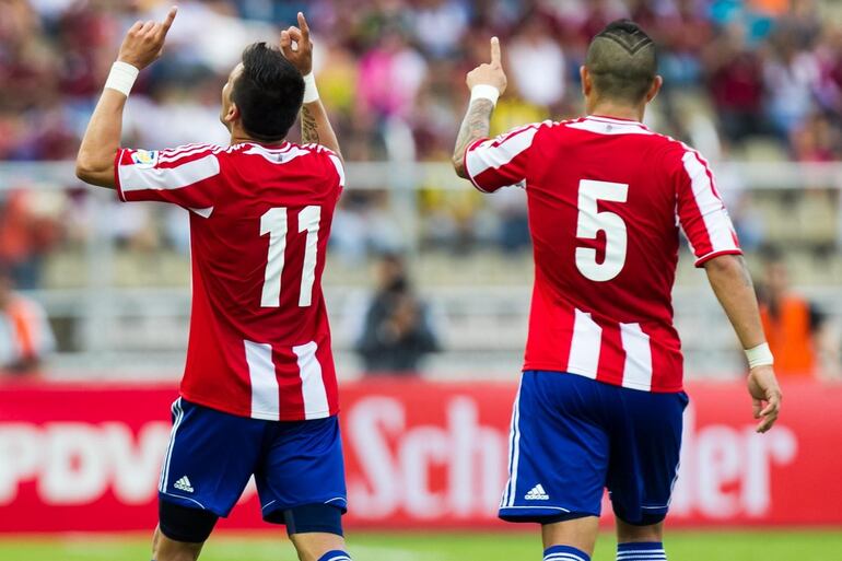 Édgar Benítez (11) y Víctor Ayala (5), jugadores de la selección paraguaya, festejan un gol en el partido contra Venezuela por las Eliminatorias Sudamericanas al Mundial Brasil 2014.