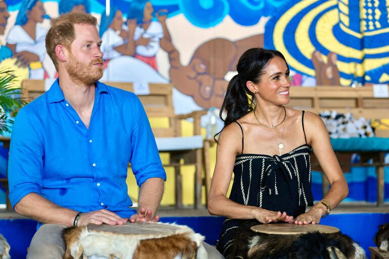 Esta fotografía publicada por la Vicepresidencia de Colombia muestra al príncipe Harry de Gran Bretaña, y a su esposa Meghan Markle tocando la batería en la escuela de tambores La Boquilla en Cartagena, departamento de Bolívar, Colombia. (ANDRES CASTILLA / Colombian Vice-Presidency / AFP)