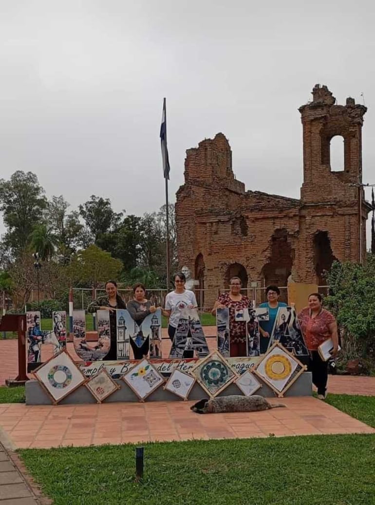 Chuco, el perro de Humaitá, posa frente a las artesanas en una exposición de productos frente a la ruina del templo San Carlos de Borromeo.