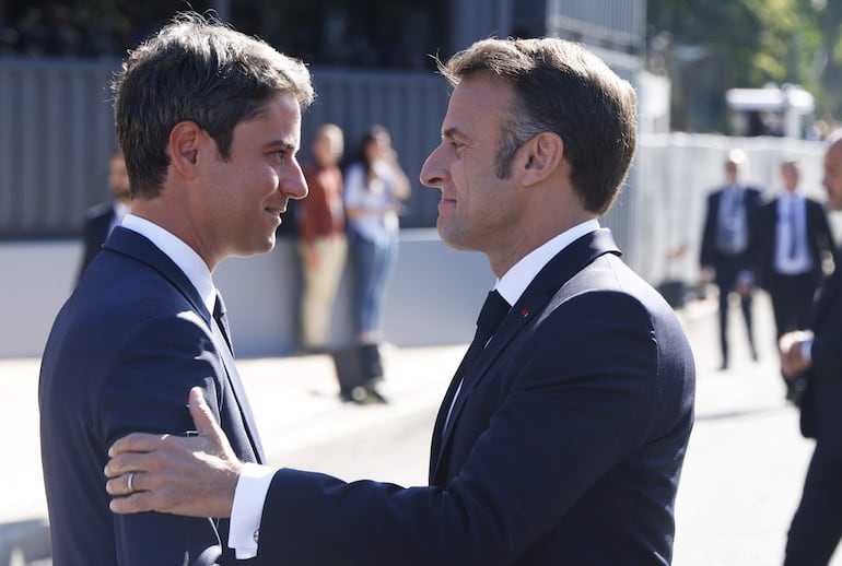 El presidente francés Emmanuel Macron (derecha) es recibido por el primer Ministro Gabriel Attal (L) durante el desfile militar del día de la Bastilla en la Avenida Foch en París. El presidente francés, Emmanuel Macron, aceptará antes del final de la jornada de este martes la dimisión del Gobierno, aunque le pedirá que siga en funciones para gestionar los asuntos corrientes.