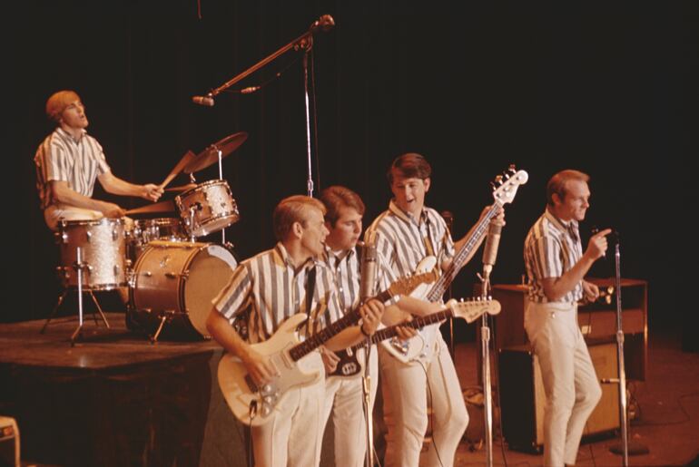 Imagen compartida por Disney que muestra a The Beach Boys durante una actuación en 1964.  Aparecen Dennis Wilson, Al Jardine, Carl Wilson, Brian Wilson, Mike Love.