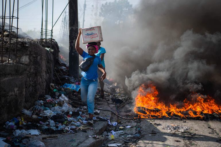 Varias personas caminan junto a cubiertas de neumáticos en llamas durante protestas contra la inseguridad en Puerto Príncipe, Haití, el pasado 19 de agosto.