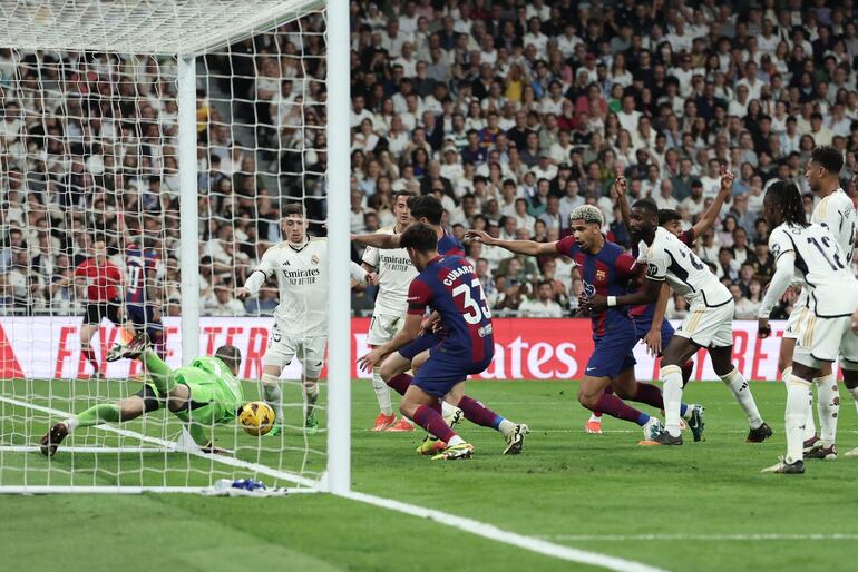 TOPSHOT - Real Madrid's Ukrainian goalkeeper #13 Andriy Lunin (L) dives for save the ball next to Barcelona's Danish defender #15 Andreas Christensen (Up L) and Barcelona's Polish forward #09 Robert Lewandowski during the Spanish league football match between Real Madrid CF and FC Barcelona at the Santiago Bernabeu stadium in Madrid on April 21, 2024. (Photo by Thomas COEX / AFP)