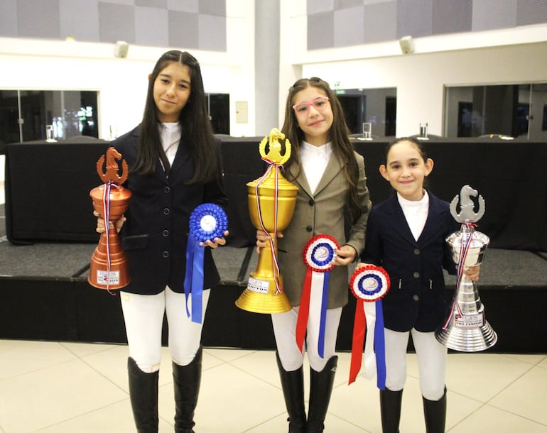 Azul Ayala (centro), campeona de Escuela Menor 0.90, flanqueada por María Paz Lovera (3ª) y Violeta Báez (2ª).