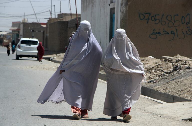 Mujeres afganas vestidas con Burqa caminan por una carretera en Kandahar, Afganistán. Decenas de mujeres afganas publicaron este jueves en redes sociales varios videos en los que se les observa cantando, en señal de protesta por la última restricción impuesta por los talibanes en Afganistán, que prohibieron el sonido en público de la voz femenina.