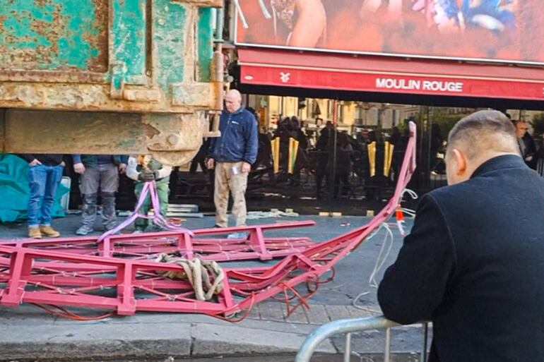 Una captura de pantalla de un vídeo de la AFP filmado en París el 25 de abril de 2024 muestra las aspas del cabaret musical Moulin Rouge en la acera después de que se derrumbara durante la noche, antes de ser retiradas por los trabajadores.