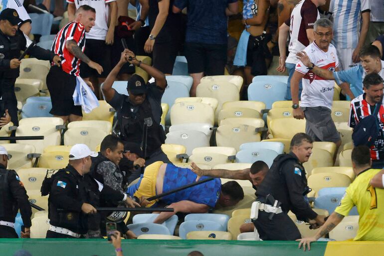 TOPSHOT - Fans of Argentina clash with Brazilian police before the start of the 2026 FIFA World Cup South American qualification football match between Brazil and Argentina at Maracana Stadium in Rio de Janeiro, Brazil, on November 21, 2023. (Photo by Daniel RAMALHO / AFP)