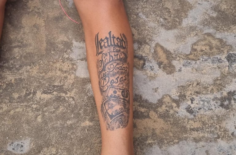 El tatuaje del detenido, con la frase "Lealtad sobre todas las cosas" junto con gráficos de fajos de billetes, que hace alusión al clan Rotela.