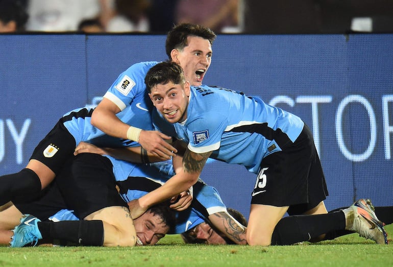 Uruguay's midfielder #05 Manuel Ugarte (bottom) celebrates with teammates after scoring his team third goal during the 2026 FIFA World Cup South American qualifiers football match between Uruguay and Colombia at the Centenario stadium in Montevideo on November 15, 2024. (Photo by DANTE FERNANDEZ / AFP)