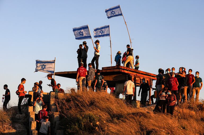 Colonos israelíes se manifiestan en las cercanías de la ciudad palestina de Halhul, en el norte de Hebron, Cisjordania.