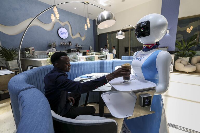 Baraka Learat agarra el café que le entrega una moza robot en el Robot CafÈ, de Kenia. 