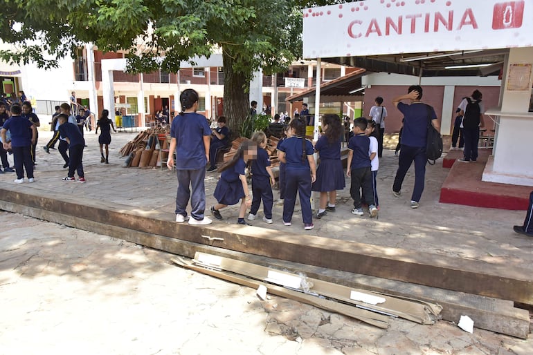 Niños suben y saltan entre las enormes vigas de madera que están en la entrada de la escuela Talavera Richer de Lambaré.