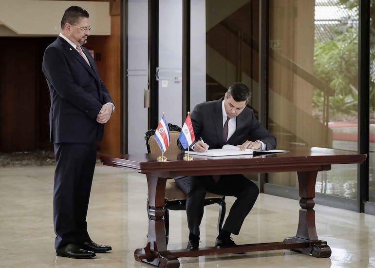 El presidente Santiago Peña (d), firma un libro junto al presidente de Costa Rica, Rodrigo Chaves, este lunes en la Casa Presidencial, en San José (Costa Rica).