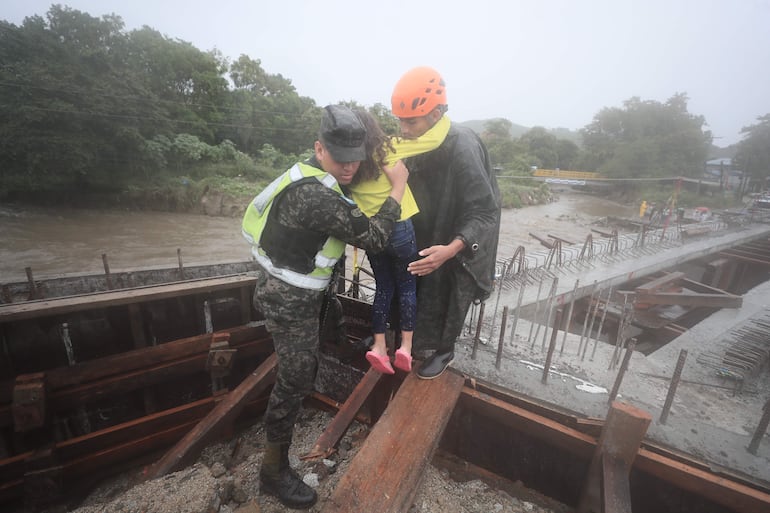 Militares y integrantes de los cuerpos de socorro de Honduras ayudan a evacuar habitantes debido a las crecidas de ríos y quebradas por el paso de la tormenta Sara.
