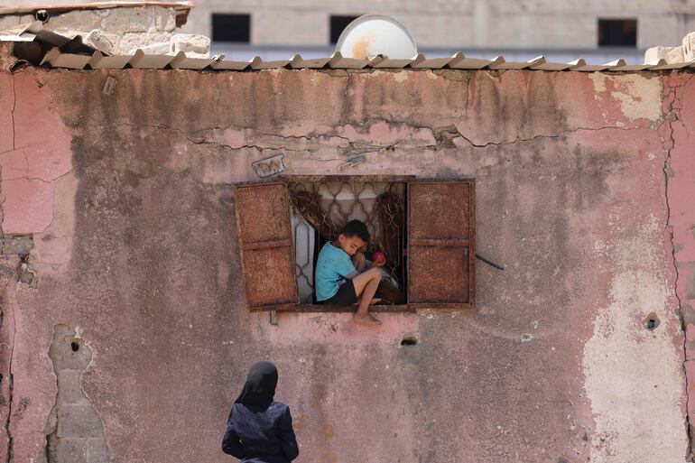 Un niño palestino se sienta en una ventana de su casa en un campo de refugiados en Gaza.