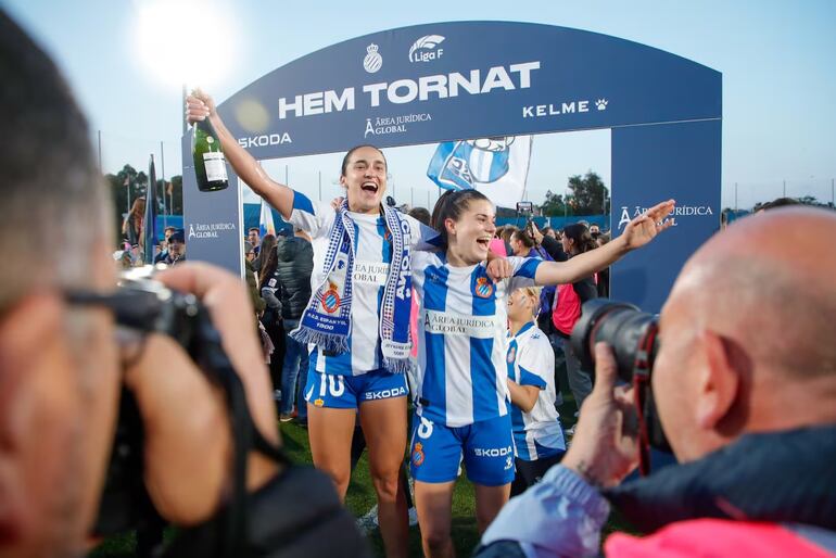 Lice Chamorro, con una botella de champagne en mano, festeja el triunfo y el ascenso del equipo de Espanyol en el campo de juego.