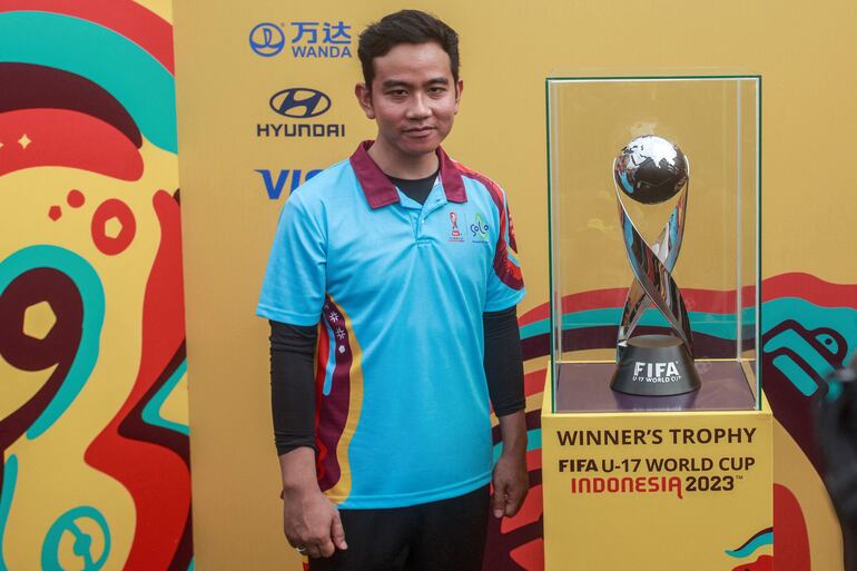 The Solo Mayor Gibran Rakabuming Raka, a vice presidential candidate and Indonesian President Joko Widodo's son, stands next to the FIFA U-17 World Cup trophy during a promotional event for the upcoming youth football tournament in Solo on November 5, 2023. (Photo by DEVI RAHMAN / AFP)