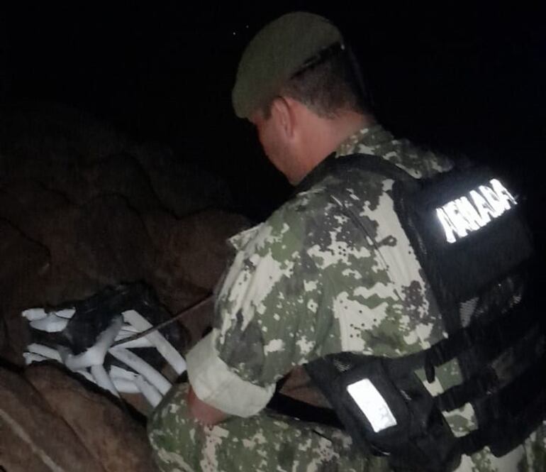 Un personal militar observa las dinamitas halladas al costado del río Paraná.