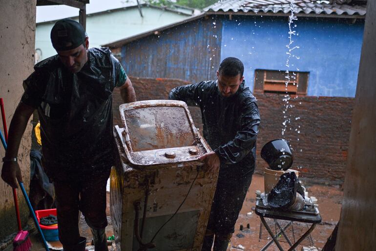 Everton Lemes (i) y su cuñado Brayon Jost cargan una heladera afectada por la inundación en el municipio de Río Pardo, estado de Rio Grande do Sul (Brasil).