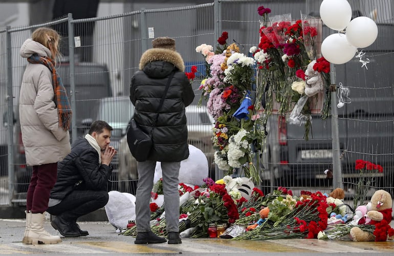 La gente llora y deja flores a la sala de conciertos Crocus City Hall tras un ataque terrorista en Krasnogorsk, en las afueras de Moscú, Rusia, el 23 de marzo de 2024.