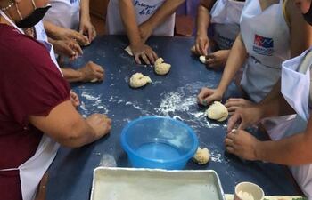Un grupo de mujeres participa de un curso de panadería, con los elementos de protección dados por la Sinafocal.