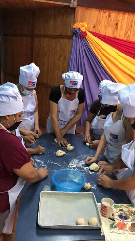 Un grupo de mujeres participa de un curso de panadería, con los elementos de protección dados por la Sinafocal.