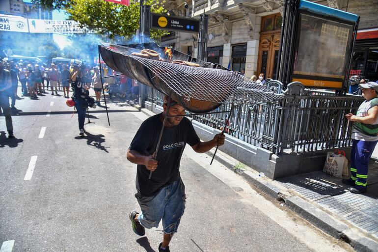 Un hombre corre con un asador en su cabeza durante una protesta convocada por la Confederación General del Trabajo hoy, en Buenos Aires (Argentina). El secretario general de la Confederación General del Trabajo (CGT), Héctor Dáer, dijo este miércoles que los sindicatos y organizaciones sociales seguirán luchando en Argentina hasta que caigan las iniciativas reformistas de Javier Milei.