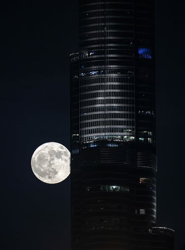 La Luna llena, también llamada Super Luna Azul, se eleva detrás del edificio más alto del mundo, Burj Khalifa, en el emirato del Golfo de Dubai, Emiratos Árabes Unidos.